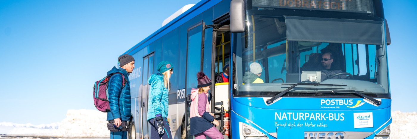 Menschen beim Einsteigen in das Naturpark Dobratsch Shuttle im Winter