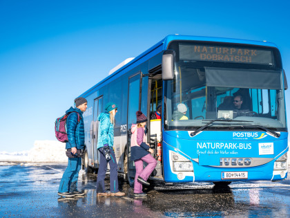 Menschen beim Einsteigen in das Naturpark Dobratsch Shuttle im Winter
