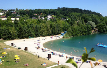 Freibad Wernberg ist ein Baggerteich mit Strand und Liegewiese mit Blick auf eine n Wald